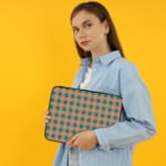 Infidu checkered beige and green laptop sleeve with a modern and colorful pattern. the person holding the sleeve