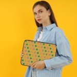 Infidu Green and Pink Star Pattern Laptop Sleeve with small green and pink stars on a light green background, displayed on a desk. the person holding the sleeve