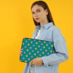 Playful pastel polka dot design laptop sleeve with yellow, purple, and orange dots on a teal background. the person holding the sleeve