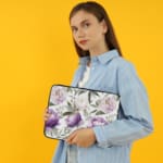 Elegant floral laptop sleeve with purple flowers and green leaves on a soft, light background. the person holding the sleeve