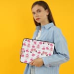 Infidu pink & white laptop sleeve with coffee cups, sofas, and hearts design on a white background. the person holding the sleeve