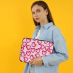 Infidu Pink Heart Pattern Laptop Sleeve with a playful design of large, evenly spaced pink hearts on a light pink background. the person holding the sleeve