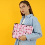 Infidu pink & white laptop sleeve with coffee cups, sofas, and hearts design on a white background. the person holding the sleeve