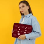 Infidu Maroon Heart & Angel Pattern Laptop Sleeve with white hearts and angel figures on a maroon background. the person holding the sleeve