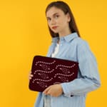 Infidu Maroon Laptop Sleeve with Heart & Wave Pattern design, featuring hearts and dotted wave lines in light colors against a maroon background. the person holding the sleeve