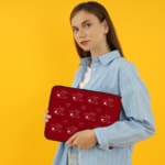 Red laptop sleeve with a playful white heart pattern on a bold red background, designed by digital artists for style and protection. the person holding the sleeve