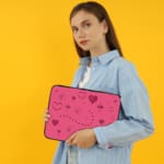 Infidu pink laptop sleeve with heart designs and dotted lines in shades of pink and purple. the person holding the sleeve