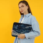 Infidu laptop sleeve with dreamy night sky design, featuring clouds and stars in dark blue and white tones. the person holding the sleeve