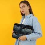 Rainy night sky laptop sleeve with stars, clouds, and a dark blue background. the person holding the sleeve