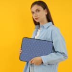 Simple blue laptop sleeve with white polka dots for a clean and stylish design. the person holding the sleeve