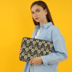 Infidu laptop sleeve with gold floral pattern on a black background. the person holding the sleeve