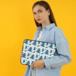 White laptop sleeve with a blue tree pattern for a nature-inspired look. the person holding the sleeve