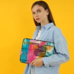 Infidu Colorful Abstract Laptop Sleeve featuring bright pink, blue, yellow, and black colors with stripes and dots on a vibrant design. the person holding the sleeve