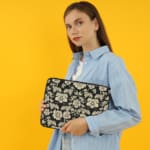 Infidu Black & Gold Floral Laptop Sleeve with a black background and detailed white floral pattern, featuring a secure zip closure. the person holding the sleeve