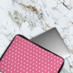 Light Pink laptop sleeve with a repeating white star pattern, shown against a bright background. The laptop sleeve covers the laptop