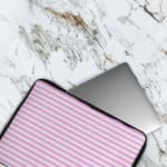 Light pink laptop sleeve with white horizontal stripes, offering a clean and minimalist design. The laptop sleeve covers the laptop