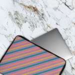 Colorful striped laptop sleeve with shades of blue, pink, yellow, and purple, offering a vibrant, playful design. The laptop sleeve covers the laptop