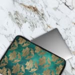 Elegant floral teal-blue laptop sleeve with beige and gold flowers, offering stylish protection for your laptop.