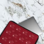 Red laptop sleeve with a playful white heart pattern on a bold red background, designed by digital artists for style and protection. The laptop sleeve covers the laptop