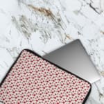 Infidu White Laptop Sleeve with Red Heart Pattern, featuring small red hearts on a white background for a playful look. The laptop sleeve covers the laptop