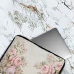 Elegant soft pink floral vintage laptop sleeve with light pink roses and green leaves on a pale background, designed for laptop protection. The laptop sleeve covers the laptop