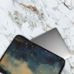 Laptop sleeve with a dark blue background featuring a starry night sky design with stars, clouds, and gradient effect. The laptop sleeve covers the laptop