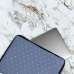 Simple blue laptop sleeve with white polka dots for a clean and stylish design. The laptop sleeve covers the laptop