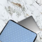 Simple blue laptop sleeve with white polka dots for a clean and stylish design. The laptop sleeve covers the laptop