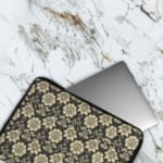 Infidu laptop sleeve with gold floral pattern on a black background. The laptop sleeve covers the laptop