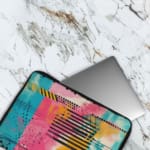 Infidu Colorful Abstract Laptop Sleeve featuring bright pink, blue, yellow, and black colors with stripes and dots on a vibrant design. The laptop sleeve covers the laptop