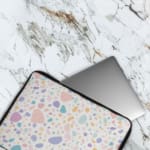 Terrazzo-style laptop sleeve with colorful spots in pink, blue, orange, and purple on a white background,