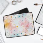 Colorful splatter paint design laptop sleeve with blue, orange, and pink splashes on a light background. laptop sleeve kept on a plain white background