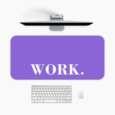 Infidu Work Desk Pad featuring the word "WORK." in white on a light purple background with a dark horizontal line above. A desk pad under the computer