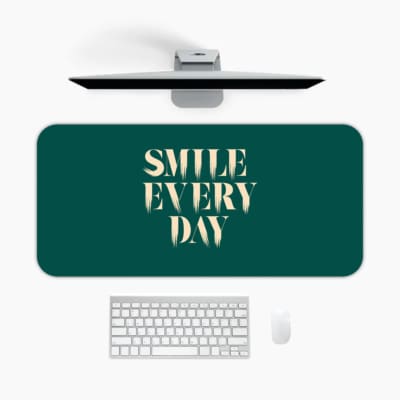 Infidu Smile Everyday Design Desk Pad featuring bold white text on a dark green background, perfect for uplifting workspaces. A desk pad under the computer