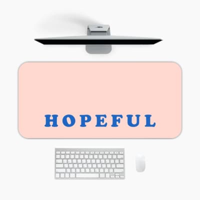 Infidu Hopeful Desk Pad with blue text on a baby pink background, motivational design A desk pad under the computer