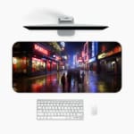 Infidu Neon City Street Design Desk Pad with a lively urban night scene, featuring neon reflections on wet pavement and silhouetted city figures. A desk pad under the computer