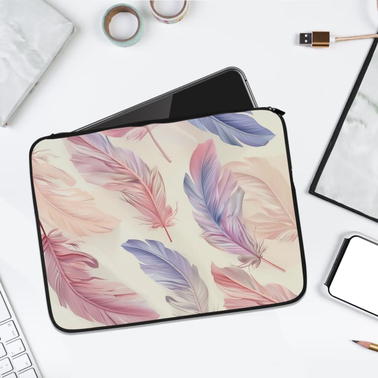 Infidu Pastel Feather Laptop Sleeve with soft pastel feathers in pink, purple, and blue on a light background, shown with office items. laptop sleeve kept on a plain white background