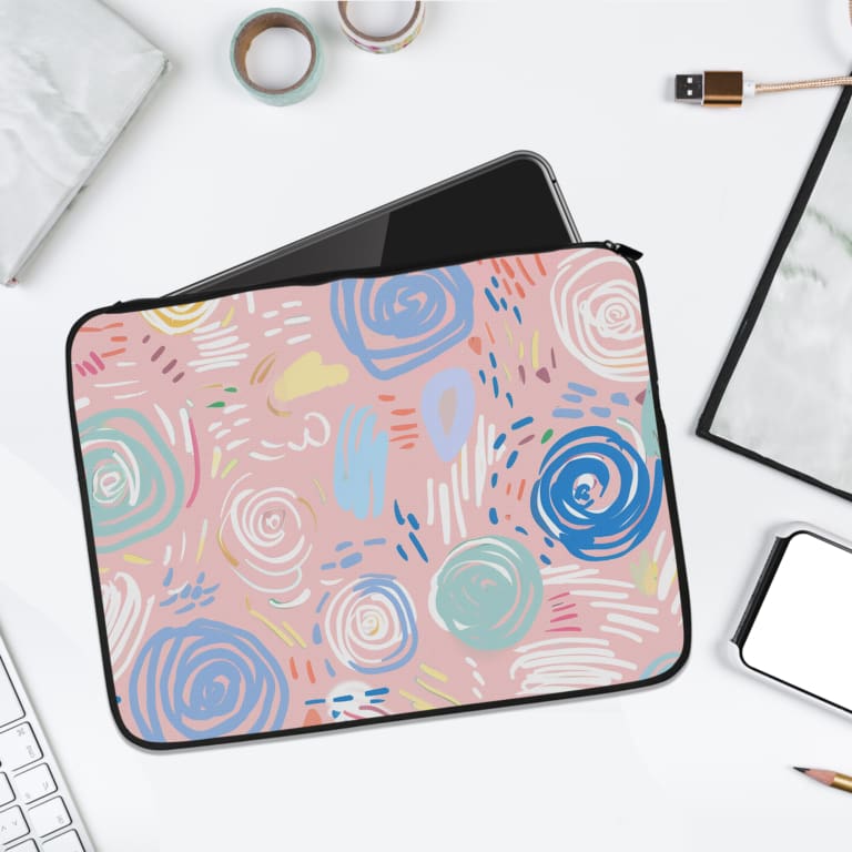 An abstract pastel laptop sleeve in pink, blue, and light green with circular and swirl patterns on a white background with a zip closure. laptop sleeve kept on a plain white background