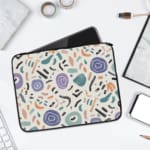 Organic abstract laptop sleeve with hand-drawn patterns in coral, purple, mint green, and black on a white background with a zip closure. laptop sleeve kept on a plain white background