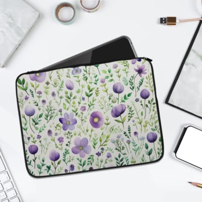 Laptop sleeve with purple floral design, featuring purple flowers and green leaves on a light background, with a secure zip closure. laptop sleeve kept on a plain white background