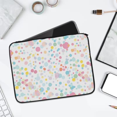 Laptop sleeve with colorful polka dots in pastel shades of pink, blue, yellow, and purple on a light background, with a secure zip closure. laptop sleeve kept on a plain white background