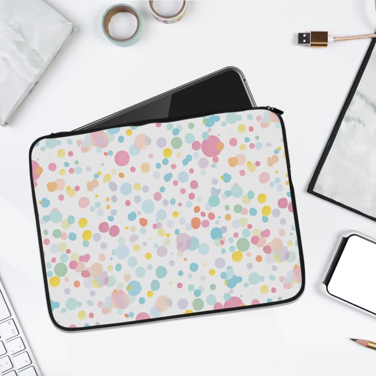 Laptop sleeve with colorful polka dots in pastel shades of pink, blue, yellow, and purple on a light background, with a secure zip closure. laptop sleeve kept on a plain white background