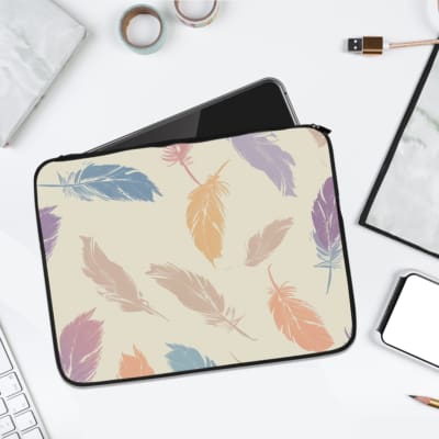 Laptop sleeve with a soft pastel feather design in pink, blue, purple, and orange on a light background, featuring a secure zip closure. laptop sleeve kept on a plain white background