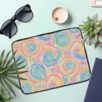 Laptop sleeve with a playful pastel spiral design on a white background. the laptop sleeve on the table