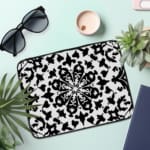 Laptop sleeve with a bold black and white floral or geometric design. the laptop sleeve on the table