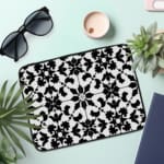 Infidu Black & White Laptop Sleeve with intricate symmetrical floral and geometric patterns, bold and stylish protective laptop case. the laptop sleeve on the table