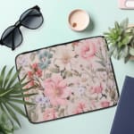 Laptop sleeve with a pastel floral design in pink, blue, and green on a white background, creating an elegant, gentle look. the laptop sleeve on the table