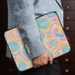 Laptop sleeve with a playful pastel spiral design on a white background. the person holding the sleeve