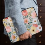 Infidu Vibrant Floral Laptop Sleeve with red, yellow, pink, and white flowers against a light background on a white desk. The laptop sleeve covers the laptop