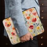 Colorful floral laptop sleeve with red, pink, yellow, and orange flowers on a light background. the person holding the sleeve